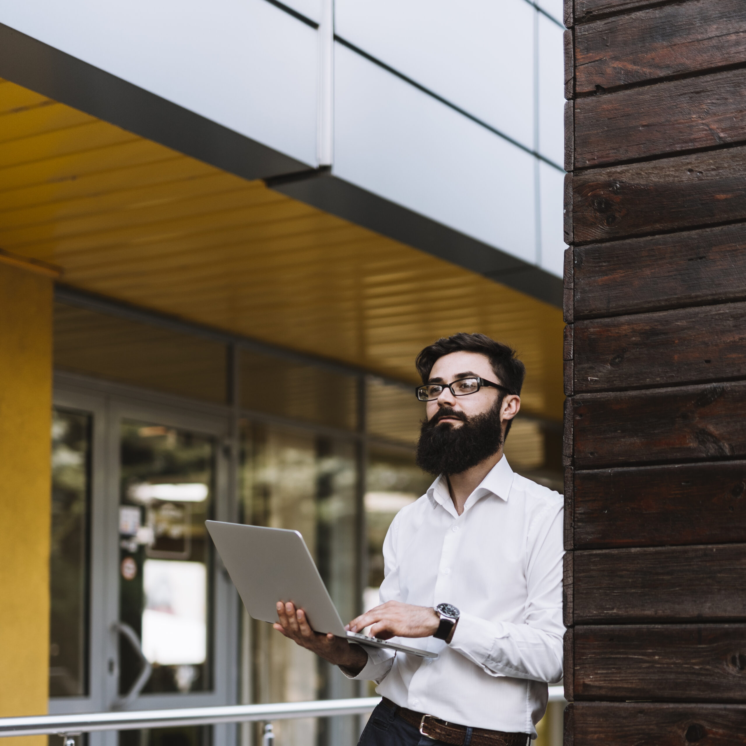 young-businessman-holding-laptop-hand-looking-away